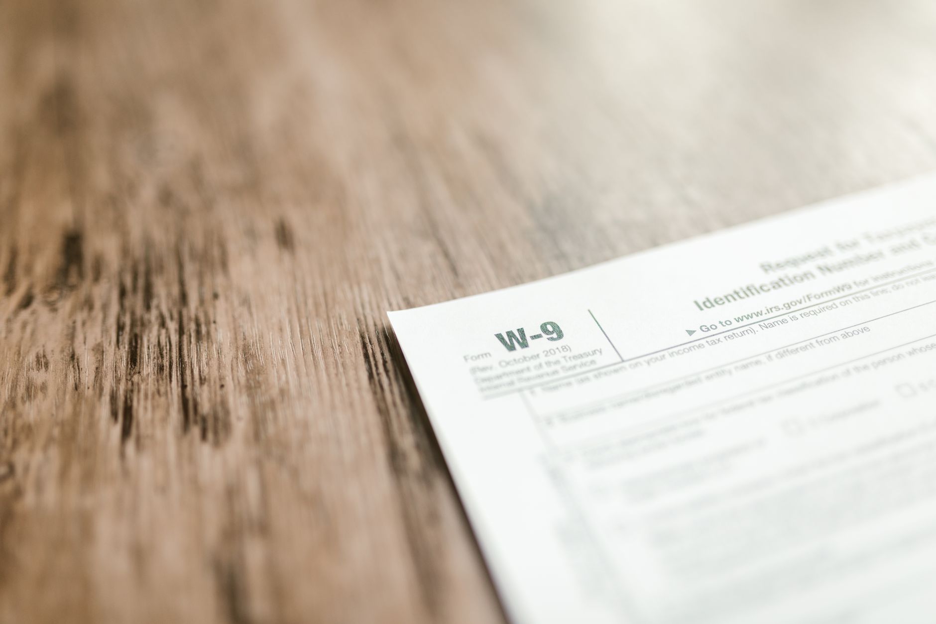 Gros plan d'un formulaire fiscal W-9 placé sur un bureau en bois, mettant l'accent sur la paperasse et la finance.